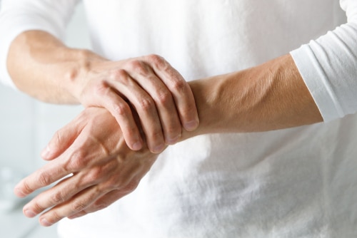 man holding his wrist due to pain caused by cervical radiculopathy