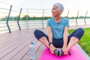 Woman on a yoga mat to relax outdoor. Senior lady prefers healthy lifestyle