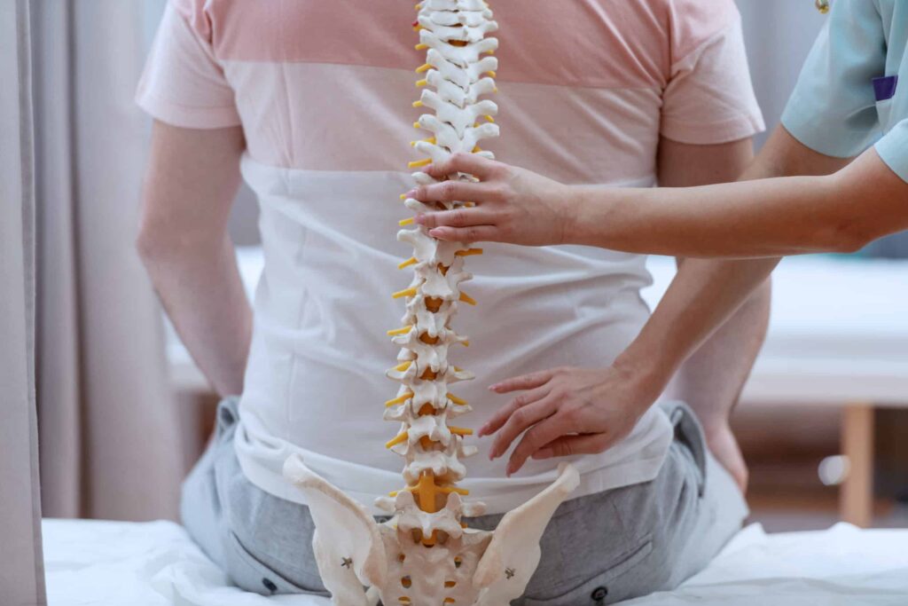 Caucasian nurse holding spine model against the patients backs. Clinic interior. iStock 1151391498