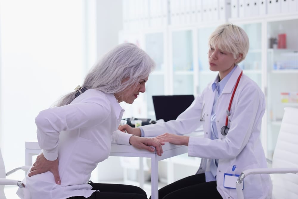 laminectomy 300x200 Doctor examining an older patient’s lower back during an evaluation for back pain.