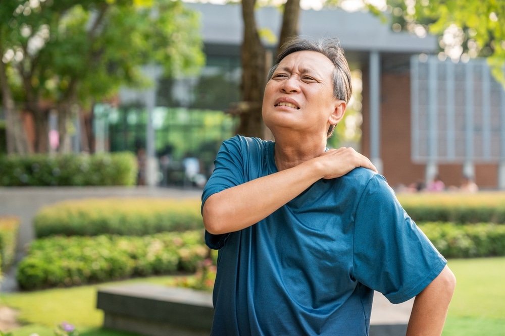 Older man holding the back of his neck with pain related to cervical nerve compression.